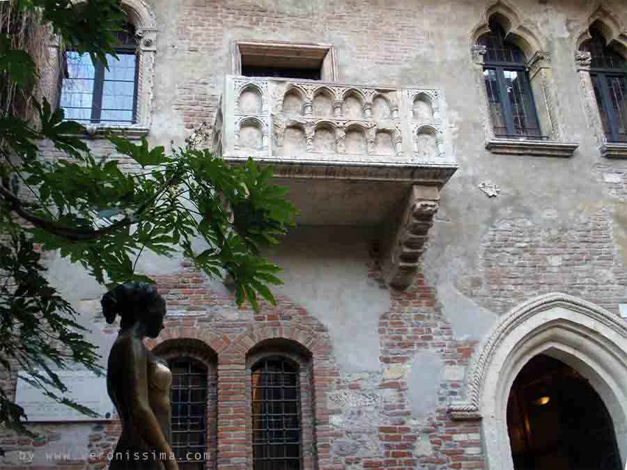 inner courtyard of Juliet's house in Verona. A woman lean out on Juliet's balcony.