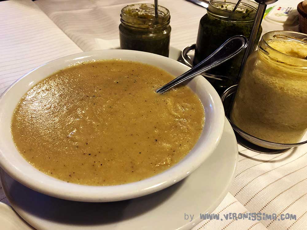 a bowl of pearà on the table with green sauce and horseradish