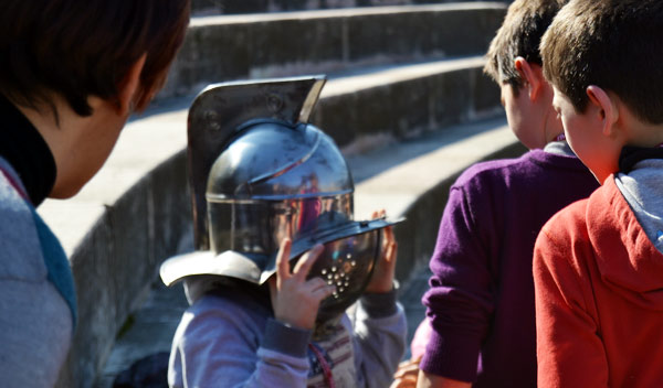 Schoolchildren try a gladiator helmet inside the Arena