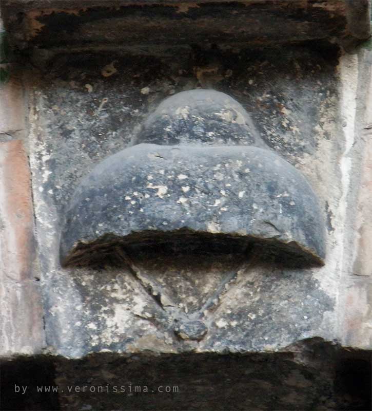 Il bassorilievo di un cappello scolpito sulla chiave di volta di un arco della casa di Giulietta