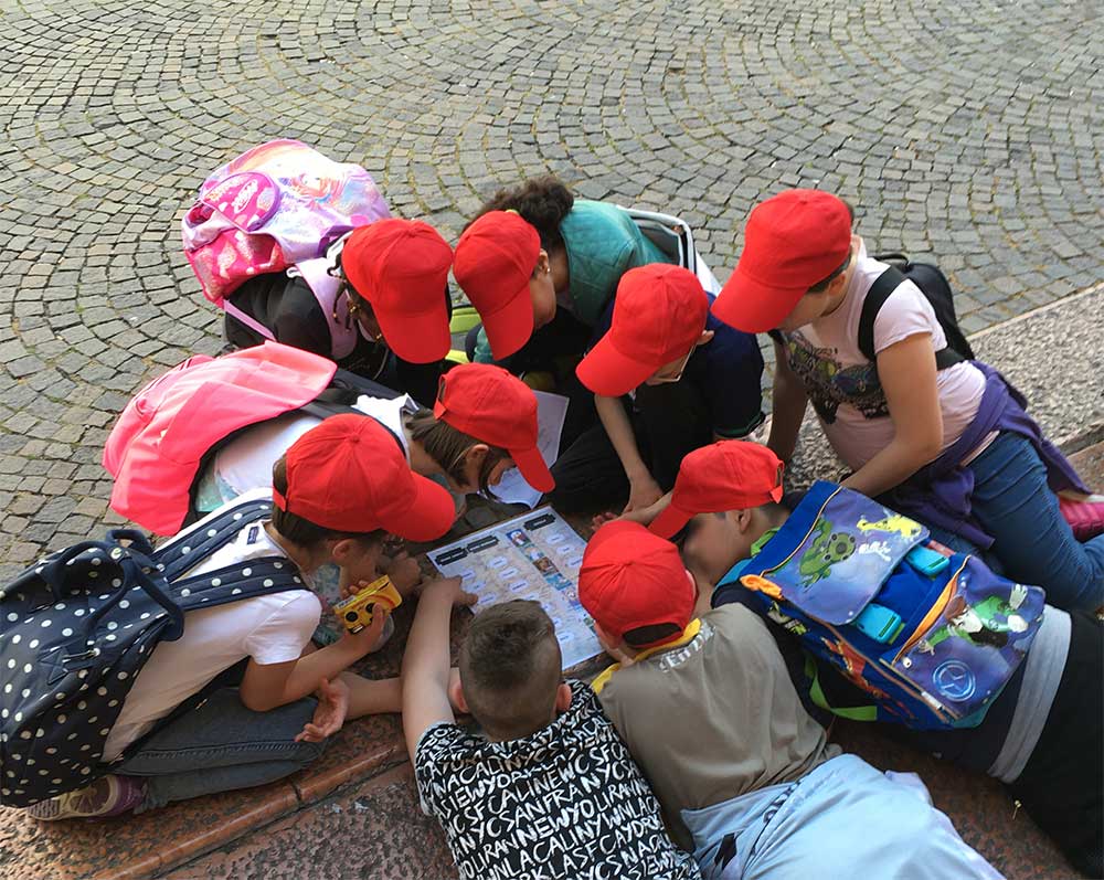 bambini stesi a terra attorno a una cartina giocano alla caccia al tesoro