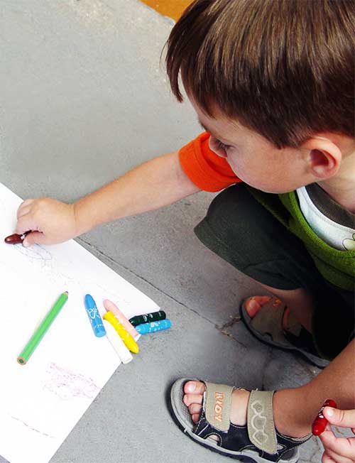 Un bambino che disegna con le matite colorate
